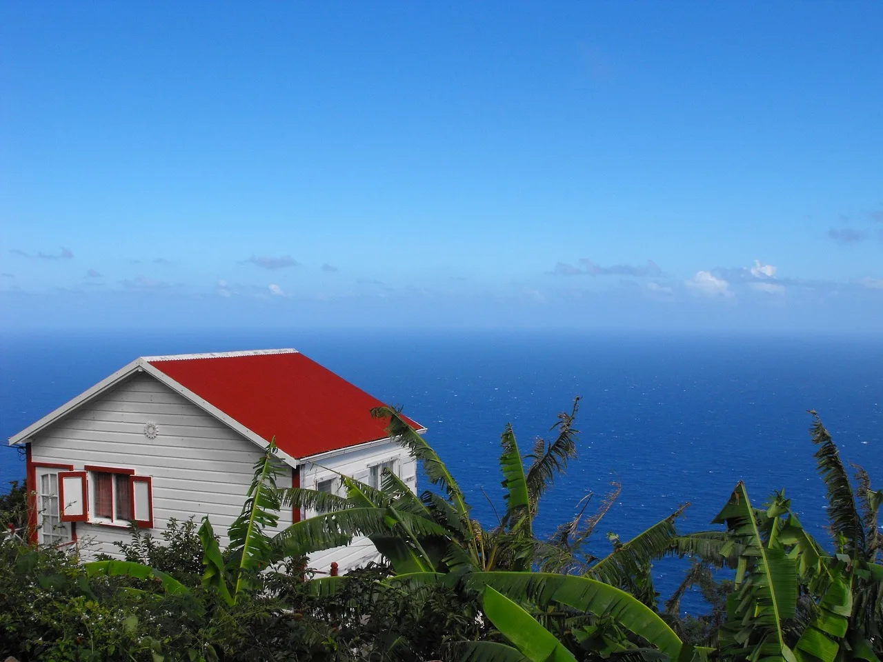 Traditional red-roofed white cottage above the sea on Saba